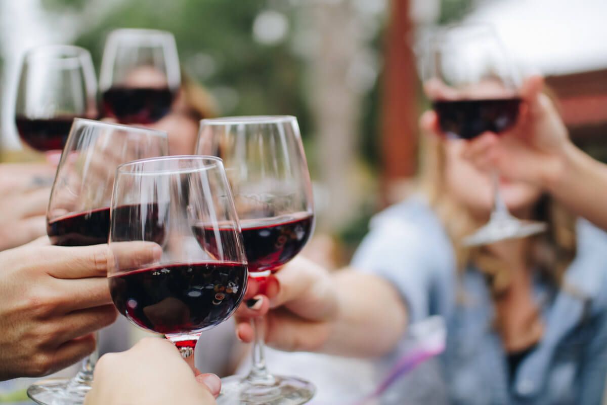 Um grupo de pessoas brindando com vinho tinto. Foto de Kelsey Knight