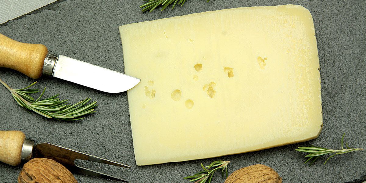 גבינת אסיאגו טרייה על קרש חיתוך.
